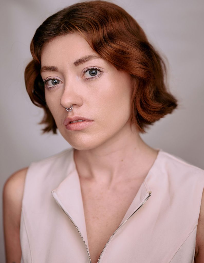 Gabriella Leondardi in headshot photography, wearing a pink shirt on a beige background.