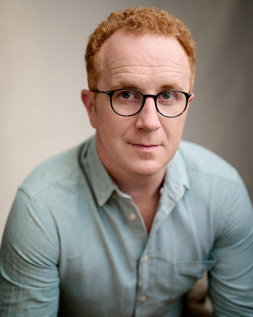 Brighton actor John Sandeman in wireframe glasses and blue shirt by Headshot Photographer Jacqui McSweeney © 2024.