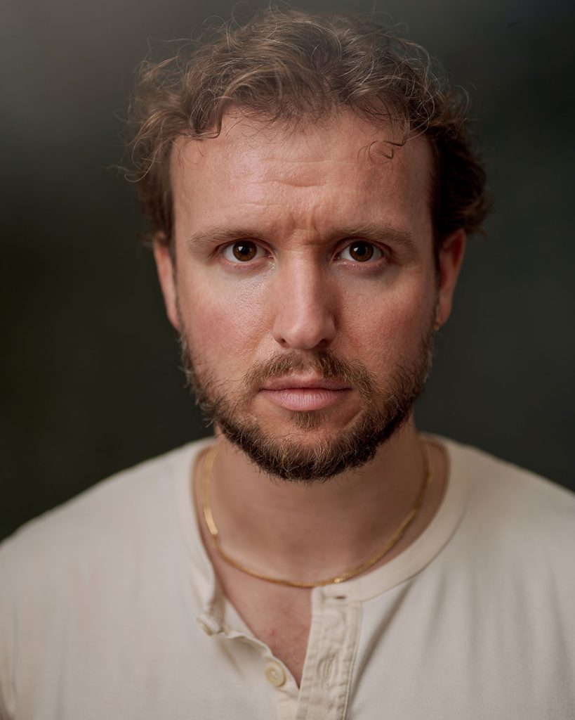 Matt Whitchurch in headshot photography, wearing a white top in the studio.