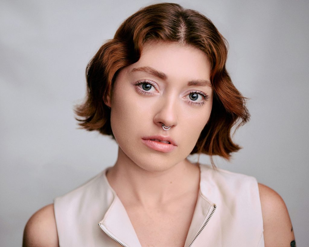Gabriella Leonardi in headshot photography, wearing a white jacket on a grey background.
